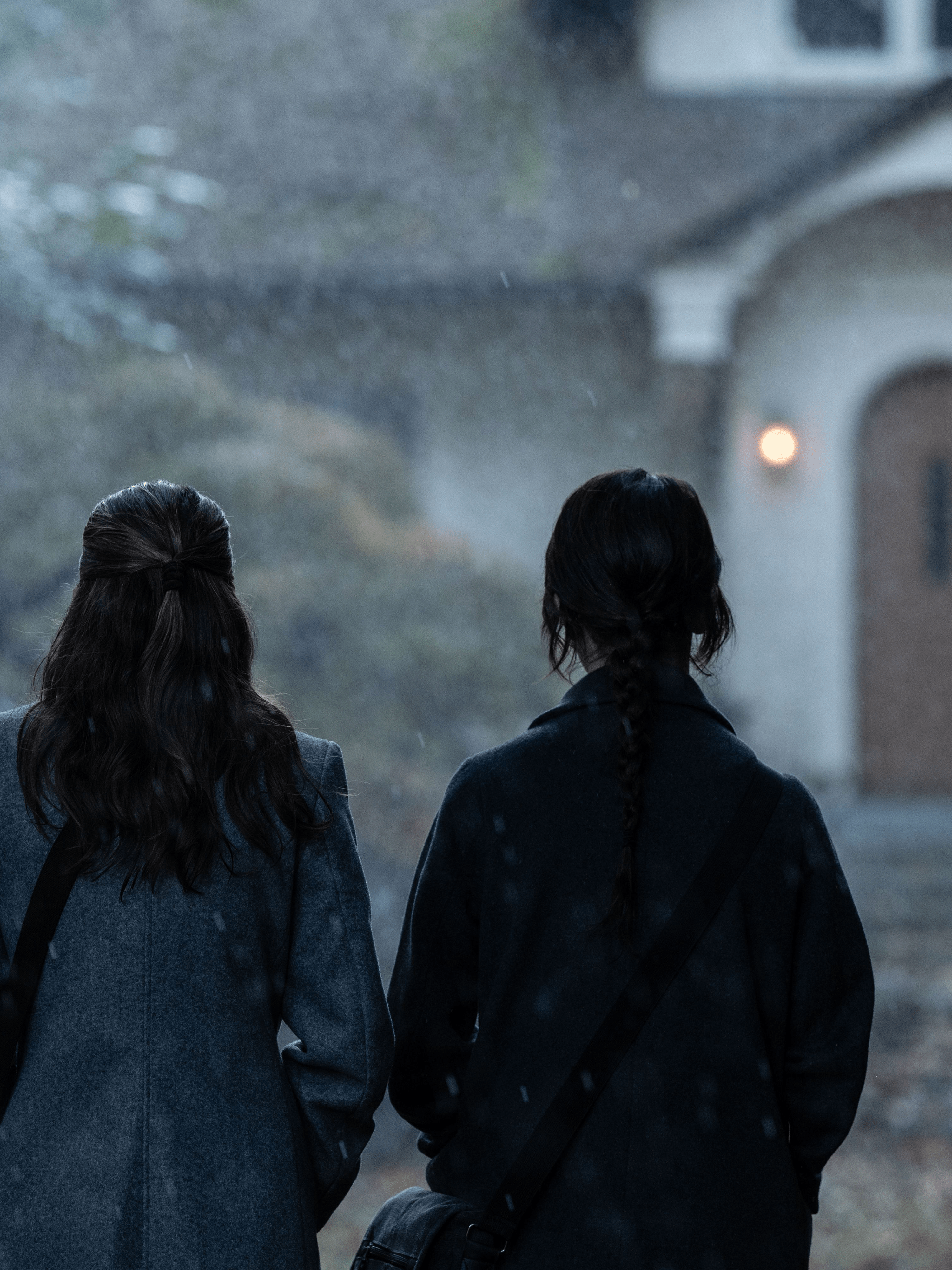 two girls with their backs to us looking at a house